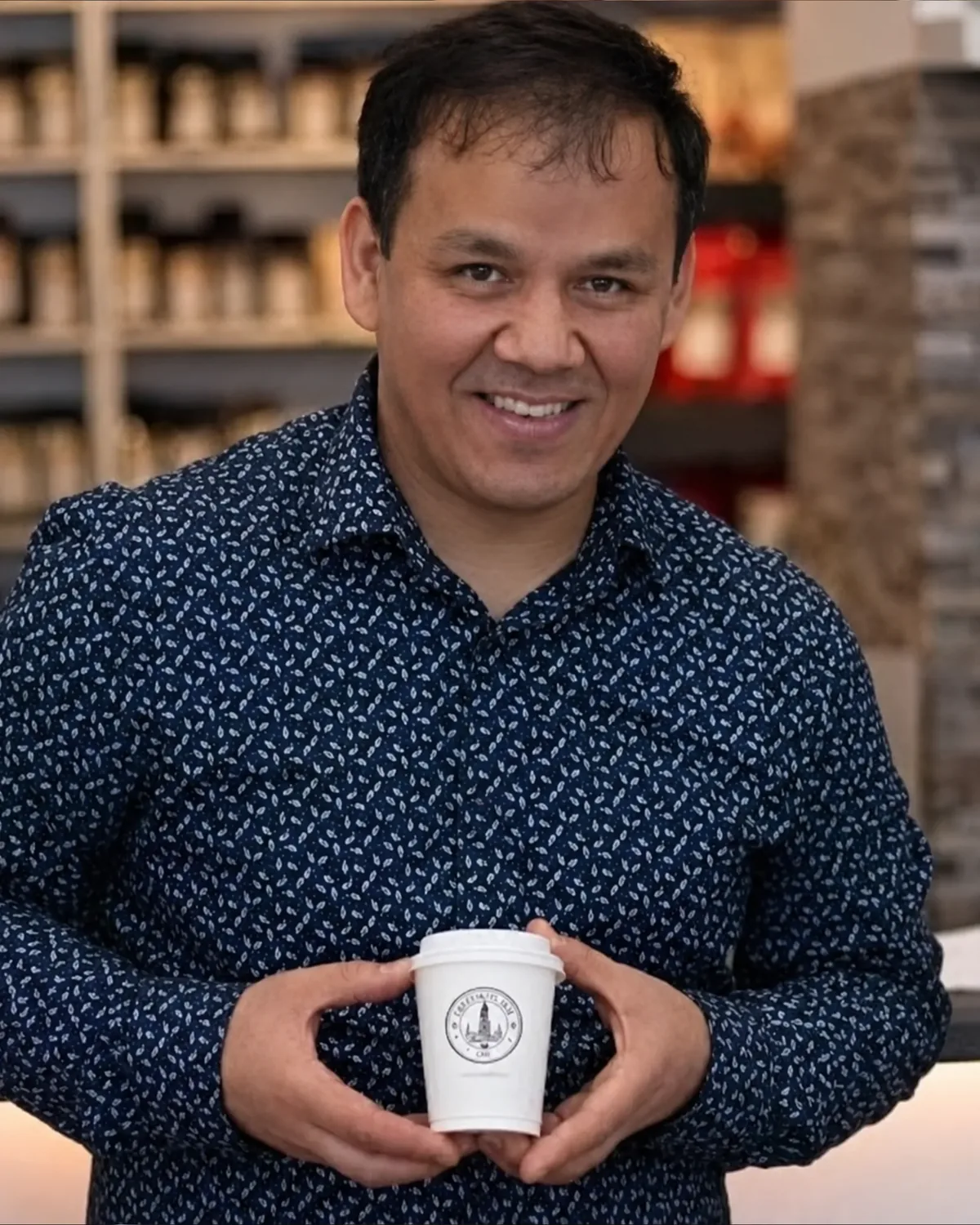 Habib Ghulamsakhi, Barista und Gründer von Cafe Latte Art, mit einem Becher im Lokal